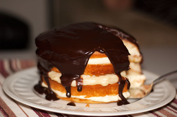 Vanilla Cake filled with Custard and Cream and Covered in Chocolate Ganache